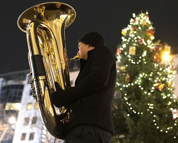 Музыкант духового оркестра Rudersdorf Music Society играет на трубе на рождественском базаре в Вене - Sputnik Узбекистан