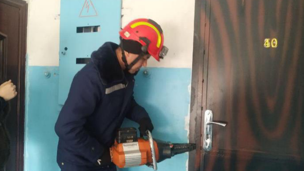 Сотрудник МЧС вскрывает дверь квартиры, чтобы вызволить запертых детей - Sputnik Узбекистан