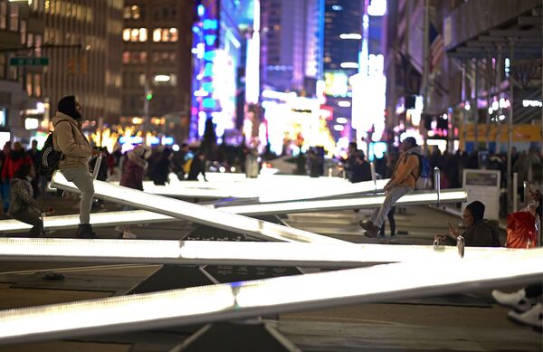 Люди катаются на светящихся качелях на Бродвее недалеко от Тайм-сквер в Нью-Йорке - Sputnik Узбекистан