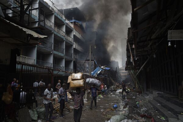Люди несут товары, спасенные от пожара, в районе рынка Балогун в Лагосе - Sputnik Узбекистан