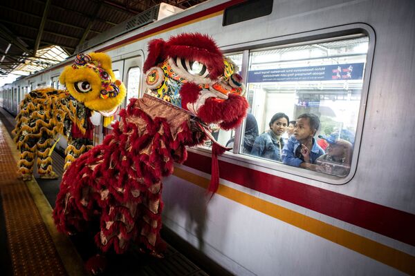  Пассажиры смотрят из окна поезда на праздничных львов во время празднования китайского лунного Нового года в Джакарте, Индонезия - Sputnik Узбекистан