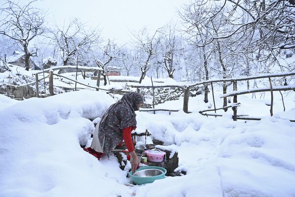 Женщина моет посуду на окраине Сринагара, где выпал снег - Sputnik Узбекистан