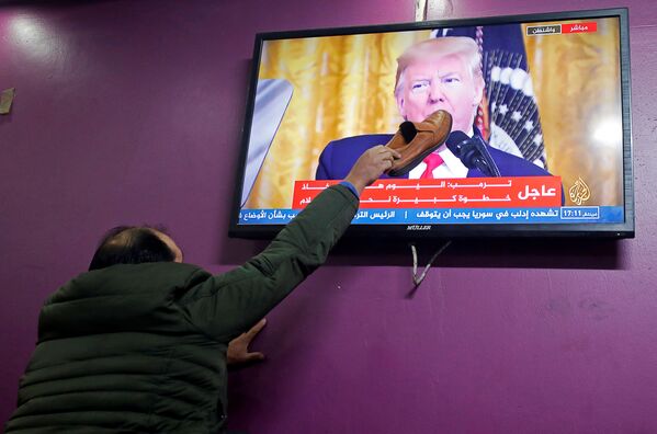 Палестинец прикладывает ботинок к экрану телевизора в кафе города Хеврон, по которому Дональд Трамп рассказывает о своем плане ближневосточного урегулирования - Sputnik Узбекистан