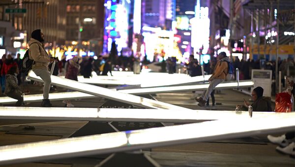 Люди катаются на светящихся качелях на Бродвее недалеко от Тайм-сквер в Нью-Йорке - Sputnik Узбекистан