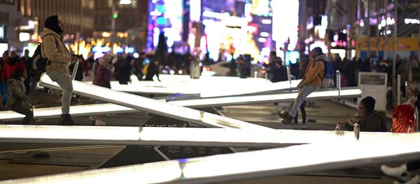 Люди катаются на светящихся качелях на Бродвее недалеко от Тайм-сквер в Нью-Йорке - Sputnik Узбекистан
