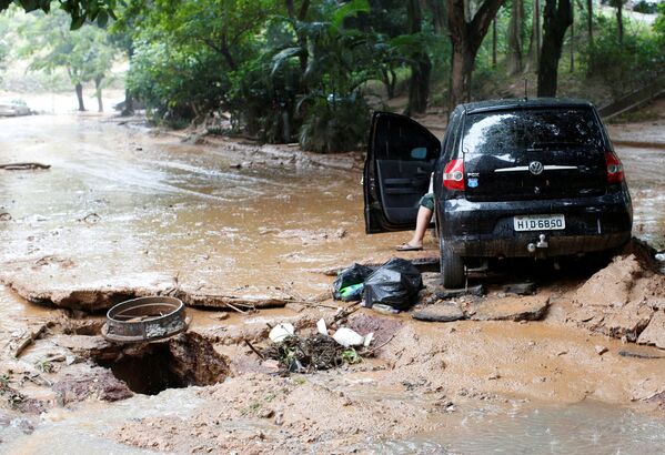 Поврежденный автомобиль и улица после сильного наводнения, вызванного дождями в Белу-Оризонти, Бразилия - Sputnik Узбекистан