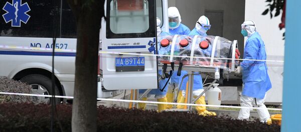 Meditsinskie rabotniki v zashitnix kostumax podnimayut izolirovannogo patsiyenta iz mashini skoroy pomoshi - Sputnik O‘zbekiston