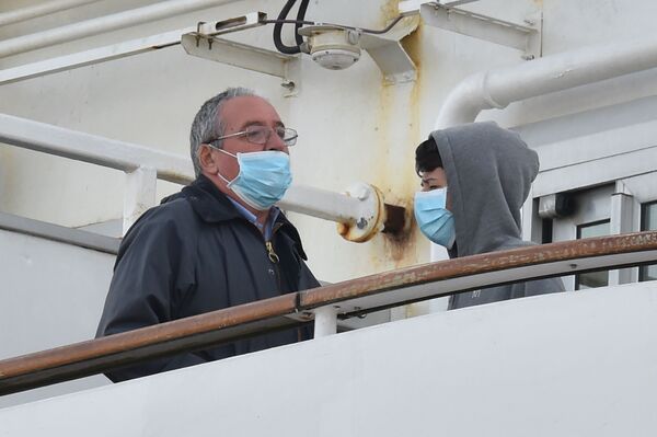 Пассажиры в медицинских масках на борту круизного лайнера Diamond Princes, помещенного в карантин у японского порта Йокогама - Sputnik Узбекистан