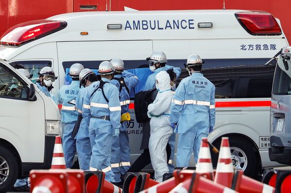Пожарные в защитных костюмах помещают в машину скорой помощи заболевших пассажиров круизного лайнера Diamond Princes, помещенного в карантин у японского порта Йокогама - Sputnik Узбекистан