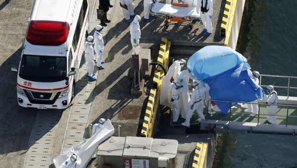 Сотрудники полиции в защитных костюмах помещают в машину скорой помощи заболевшего пассажира круизного лайнера Diamond Princes, помещенного в карантин у японского порта Йокогама - Sputnik Ўзбекистон