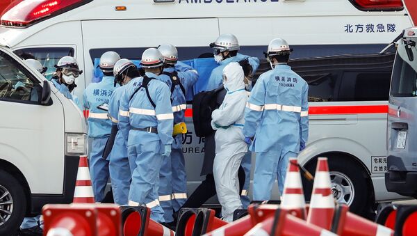 Пожарные в защитных костюмах помещают в машину скорой помощи заболевших пассажиров круизного лайнера Diamond Princes, помещенного в карантин у японского порта Йокогама - Sputnik Ўзбекистон