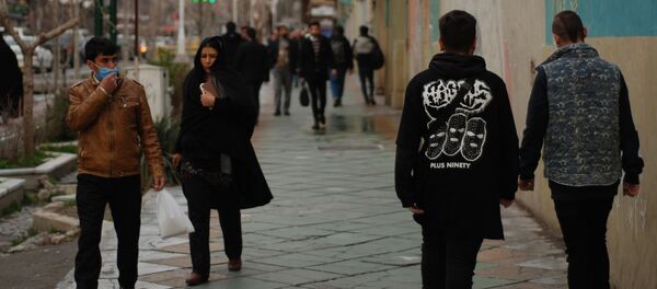 Жители Тегерана идут по одной из центральных улиц в медицинских масках Жители Тегерана идут по одной из центральных улиц в медицинских масках - Sputnik Ўзбекистон