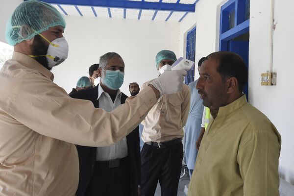 Врач проверяет температуру тела человека в городе Тафтан на пакистано-иранской границе - Sputnik Узбекистан