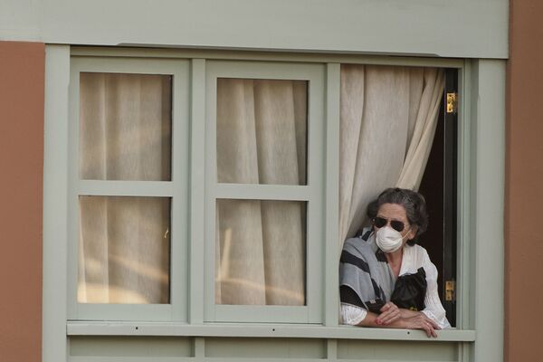 Женщина смотрит из окна Costa Adeje Palace hotel на Тенерифе - Sputnik Узбекистан