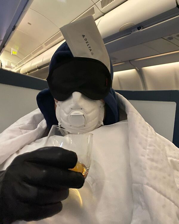 Актер Себастиан Стэн в защитном костюме и в маске во время полета на самолете - Sputnik Узбекистан