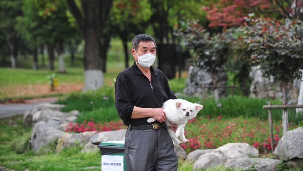 Житель Уханя в медицинской маске и с собакой в одном из парков города - Sputnik Ўзбекистон