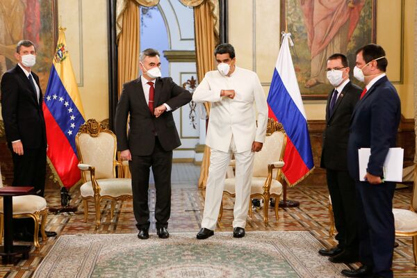 Venesuela prezidenti Nikolas Maduro va Rossiya elchisi Sergey Melik-Bagdasarov uchrashuvi. Siyosatchilar qo‘l siqish o‘rniga tirsaklarni urishtirib qo‘yishgan. - Sputnik O‘zbekiston