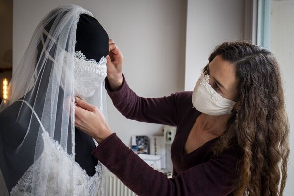 Дизайнер во время доработки свадебного платья с защитной маской в ​​магазине в Берлине - Sputnik Узбекистан