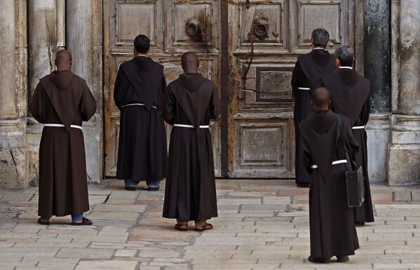 Францисканские монахи молятся перед закрытой дверью Храма Гроба Господня. - Sputnik Узбекистан