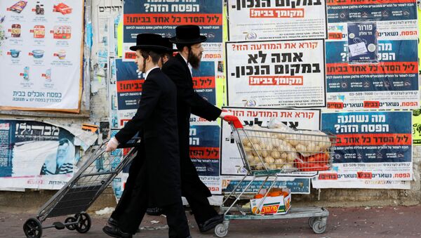 Ультраортодоксальные евреи проходят мимо информационных щитов, призывающих оставаться дома из-за коронавируса в Ашдоде, Израиль - Sputnik Узбекистан