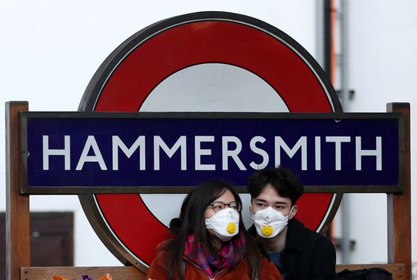 Пара в защитных масках у станции метро Hammersmith в Лондоне - Sputnik Узбекистан