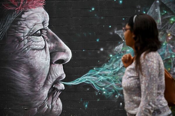 Женщина проходит мимо граффити, нарисованного в рамках фестиваля Graficalia в Кали, Колумбия - Sputnik Узбекистан