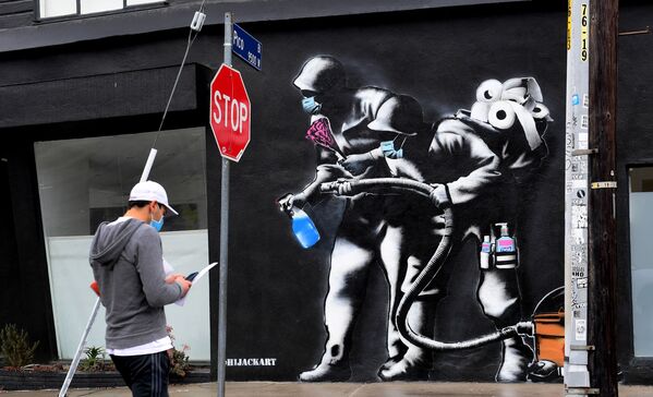 Прохожий напротив граффити, посвященного борьбе с коронавирусом, в Лос-Анджелесе - Sputnik Узбекистан