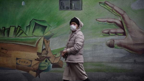 Местная жительница в Ухане, Китай, проходит на фоне стены с граффити - Sputnik Ўзбекистон