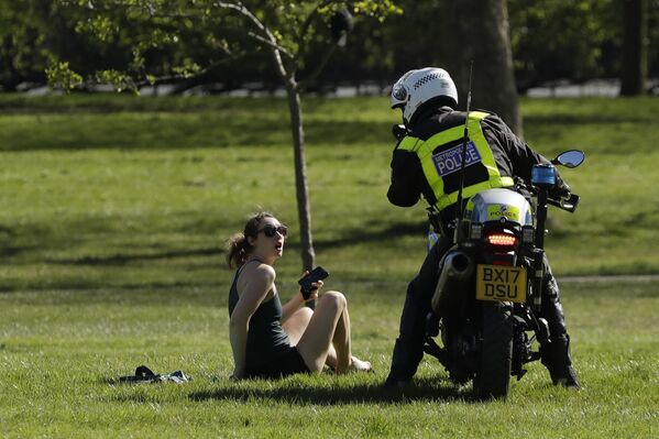 Полицейский просит посетительницу покинуть парк из-за ограничительных мер во время эпидемии коронавируса в Лондоне - Sputnik Узбекистан