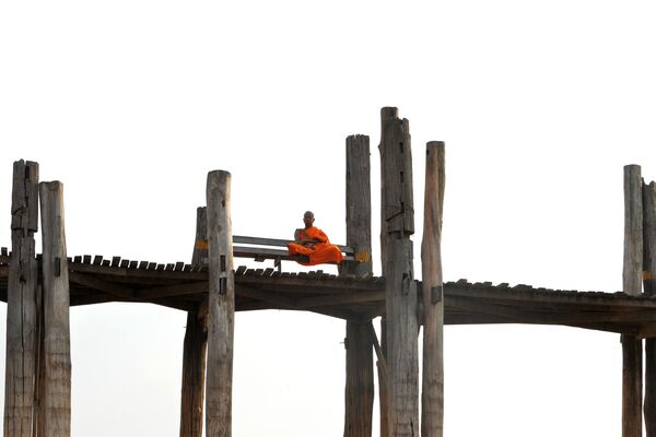 Монах, сидящий на деревянном мосту Убэйн в Амарапуре, округ Мандалай, Мьянма - Sputnik Узбекистан