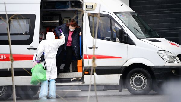 Медик скорой помощи помогает госпитализированной пациентке выйти из машины - Sputnik Ўзбекистон