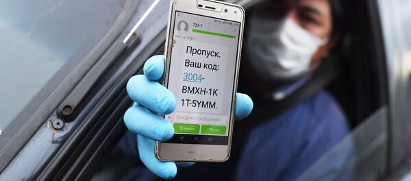 Водитель показывает код своего электронного пропуска на экране смартфона сотруднику дорожно-патрульной службы ГИБДД во время остановки на блокпосту при въезде в Москву - Sputnik Узбекистан