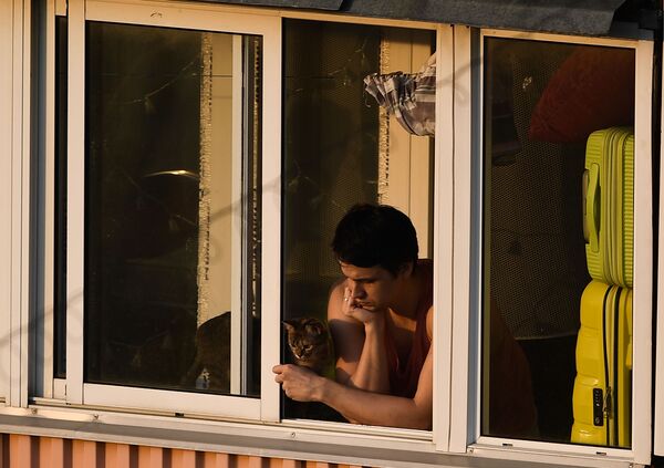 Молодой человек с кошкой на балконе многоквартирного дома в Москве - Sputnik Узбекистан