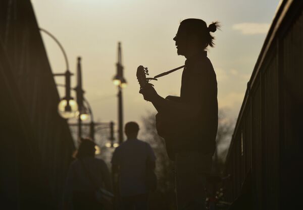 Мужчина играет на гитаре на мосту во время заката в Берлине, Германия - Sputnik Узбекистан
