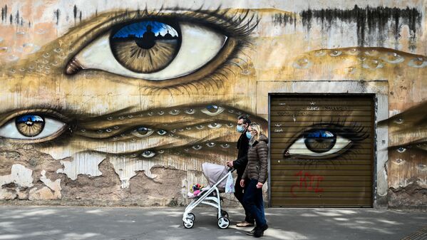 Пара в медицинских масках и с детской коляской на фоне граффити в Риме, Италия - Sputnik Узбекистан