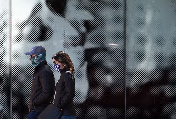 Пара в защитных масках проходит мимо афиши у кинотеатра в Вашингтоне, США - Sputnik Узбекистан