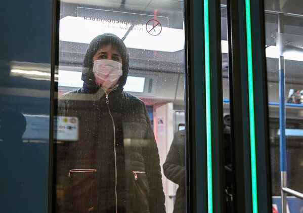 Женщина в защитной маске в вагоне поезда на станции метро Новокузнецкая в Москве - Sputnik Узбекистан