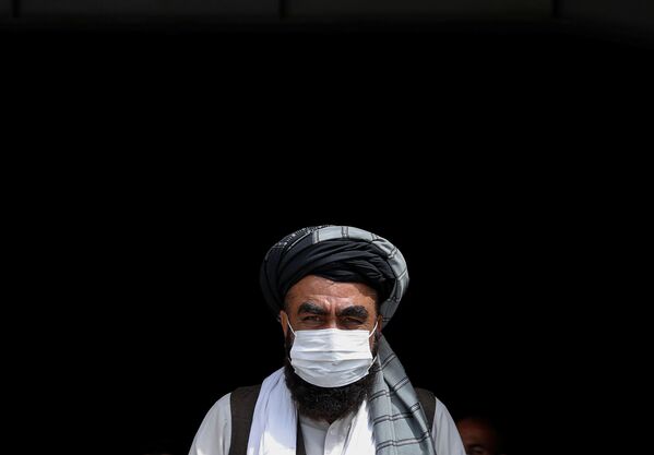 Мужчина в медицинской маске во время бесплатной раздачи продовольствия нуждающимся в Кабуле - Sputnik Ўзбекистон