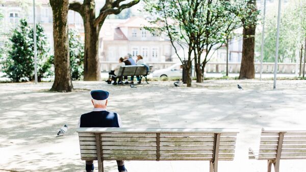 Пожилой мужчина сидит на скамейке в парке - Sputnik Ўзбекистон