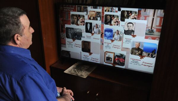 Мужчина смотрит онлайн-трансляцию акции Бессмертный полк - Sputnik Узбекистан