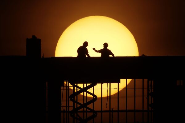 Рабочие на фоне восходящего солнца на стройке в Канзас-сити, штат Миссури, США - Sputnik Узбекистан