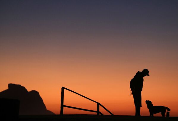 Мужчина во время прогулки с собакой на рассвете в Рио-де-Жанейро, Бразилия - Sputnik Узбекистан