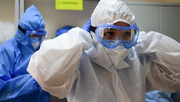 Медицинские работники одевают средства индивидуальной защиты перед входом в красную зону  - Sputnik Ўзбекистон