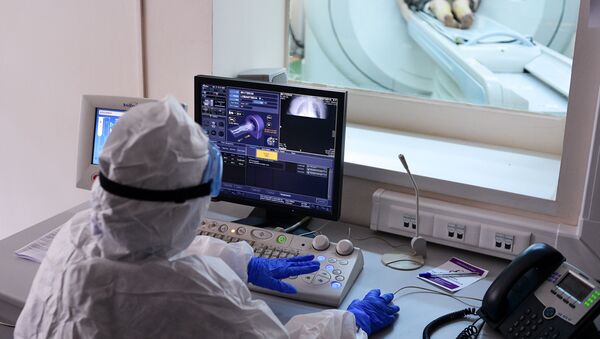 Врач смотрит показания аппарата компьютерной томографии во время обследования пациента  - Sputnik Узбекистан