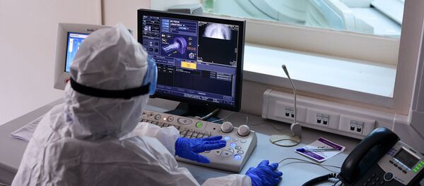 Врач смотрит показания аппарата компьютерной томографии во время обследования пациента  - Sputnik Узбекистан