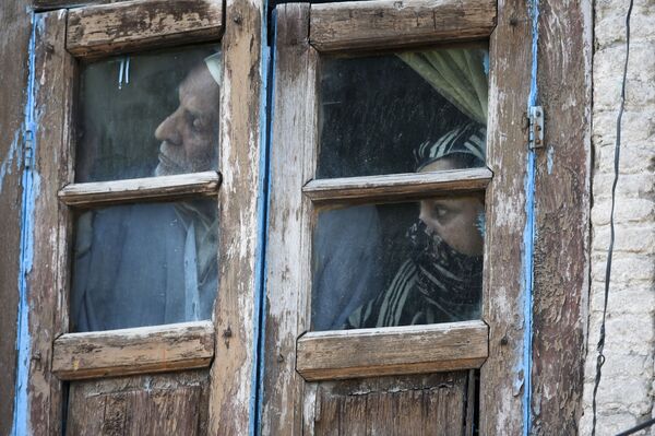 Люди смотрят из окна своего дома в Сринагаре, Индия. - Sputnik Узбекистан