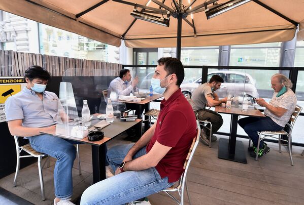 Люди в защитных масках сидят на террасе ресторана в Милане, Италия - Sputnik Узбекистан