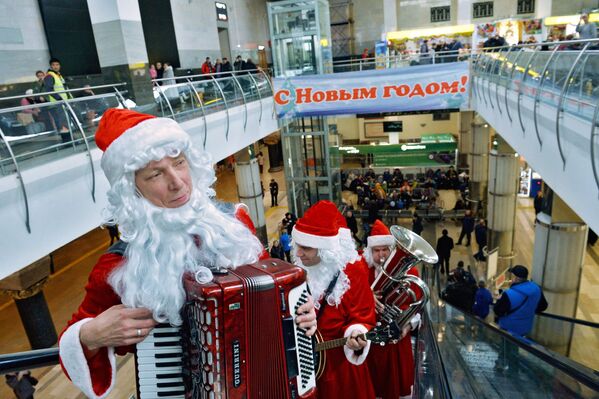 Музыканты в костюмах Дедов Морозов играют для пассажиров московских вокзалов - Sputnik Узбекистан
