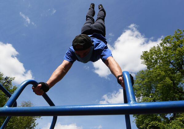 Молодой человек во время выполнения физических упражнений в парке ДК Химиков в Казани - Sputnik Ўзбекистон