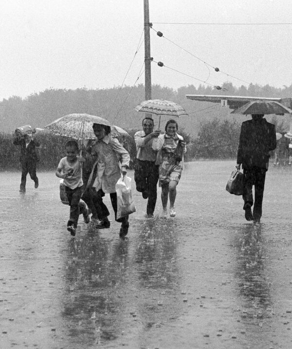 Жители города Тырныауз бегут под дождем. - Sputnik Узбекистан